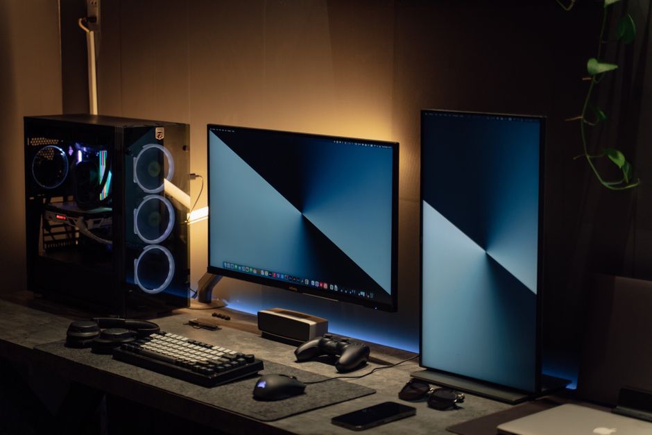 Moderni PC setup s dva monitora u zatamnjenoj prostoriji