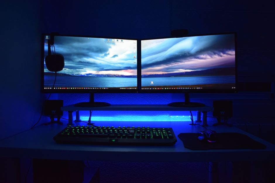 Dva monitora s plavom rasvjetom na gaming stolu